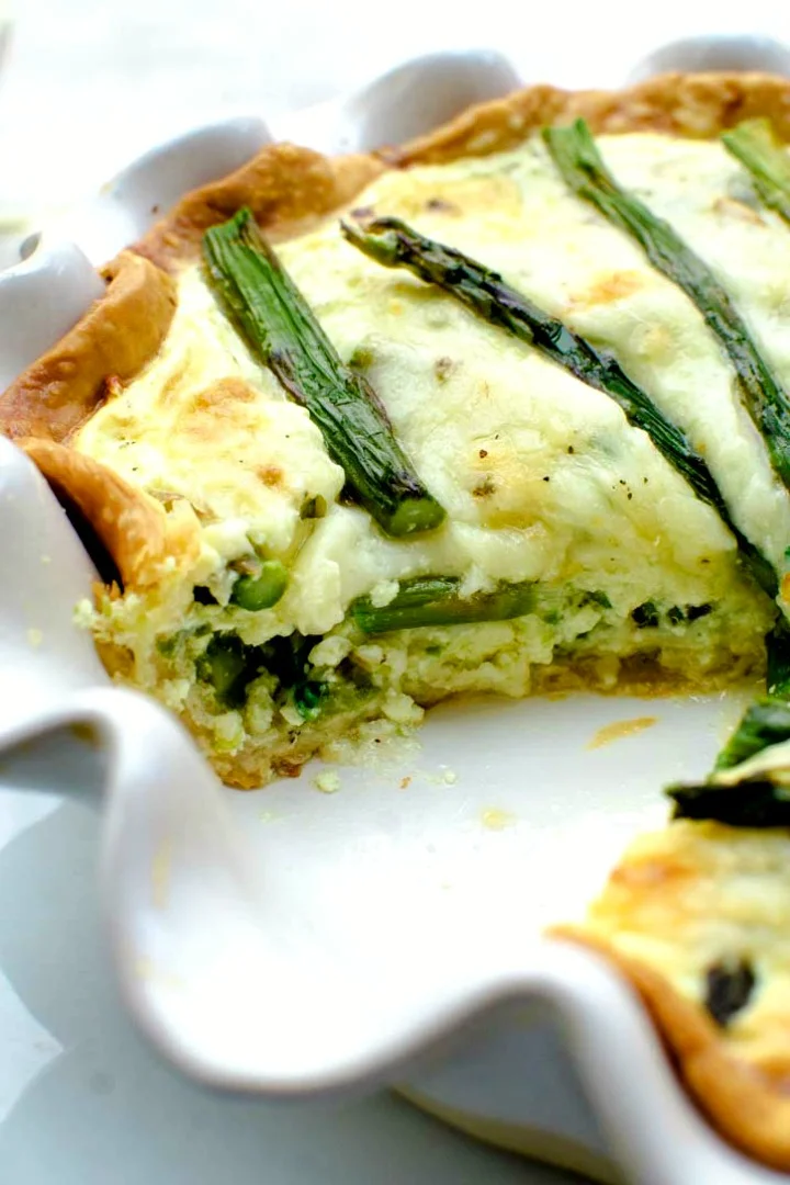 Asparagus quiche is a vegetarian quiche recipe perfect for a spring holiday brunch or weeknight dinner. Savory egg custard pie with asparagus and cheese. #asparagus #quiche #brunchrecipes #Easter side view of vegetarian quiche with asparagus