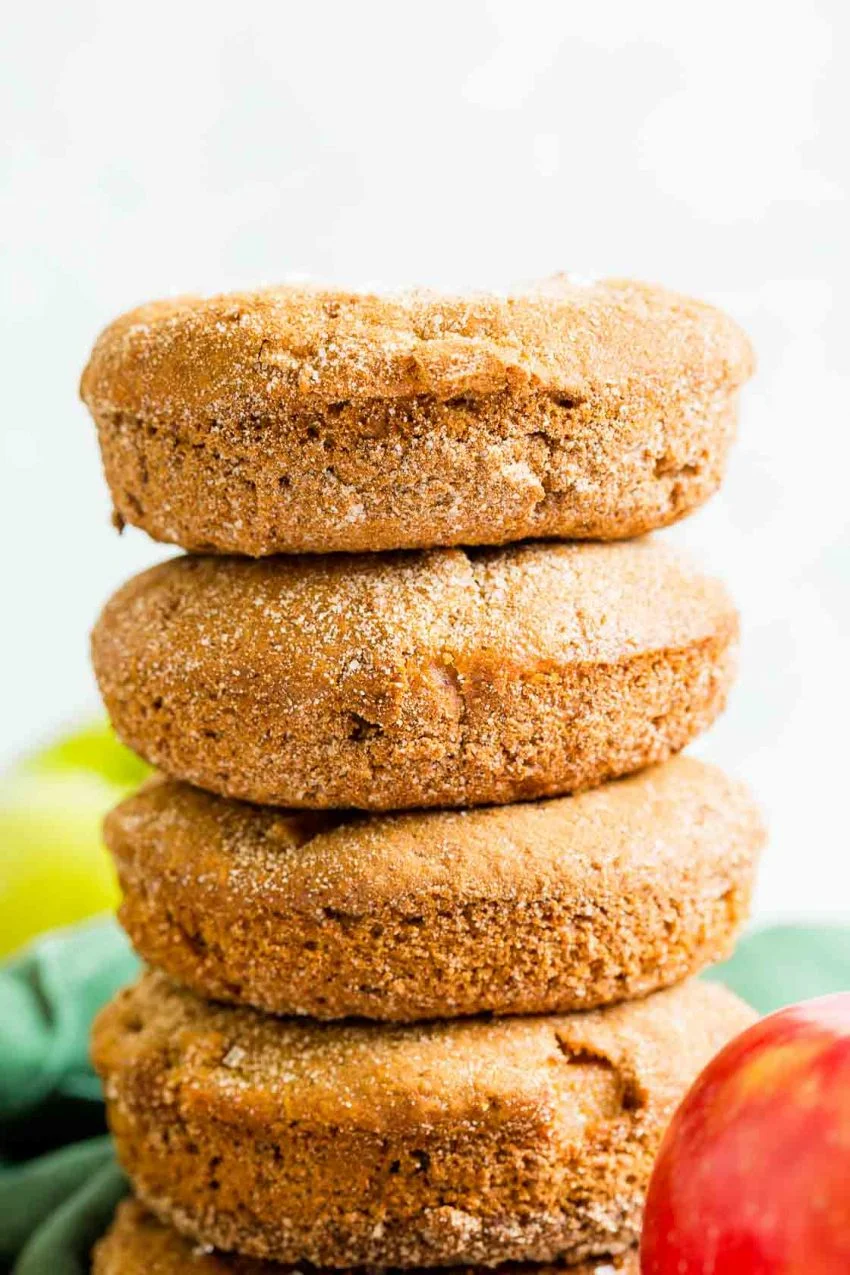 A close up stack of cinnamon apple donuts with cinnamon sugar topping.