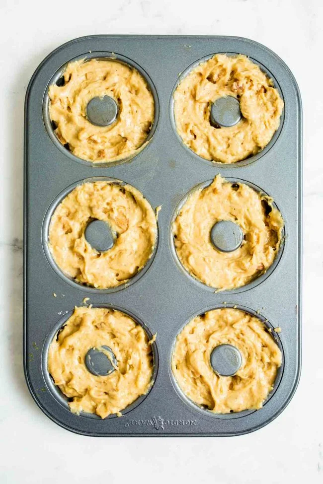 An overhead photo of a donut pan with apple cinnamon batter.