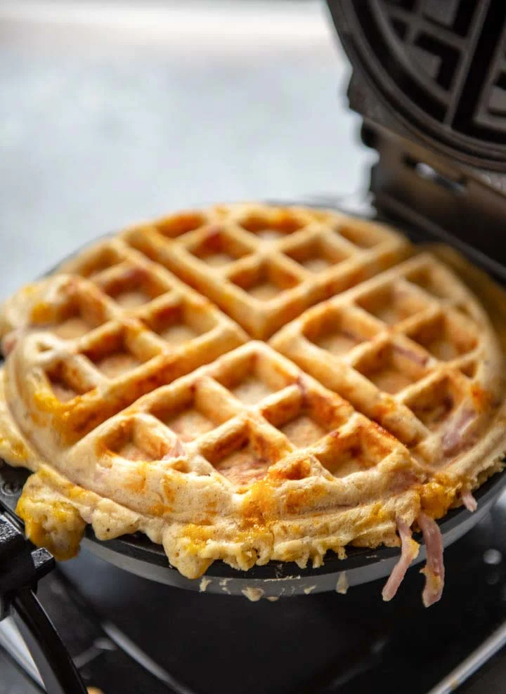 These savory waffles are a big hit for weekend brunch or weeknight dinner. They freeze well, so be sure to make a double batch! This stuffed waffles recipe uses leftover Easter ham and cheddar cheese. #waffles #leftoverham #brunch #recipes homemade waffle in a waffle iron