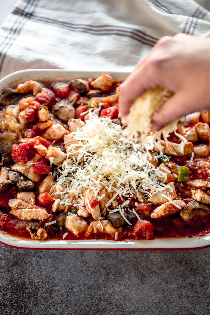 sprinkling cheese onto a chicken casserole