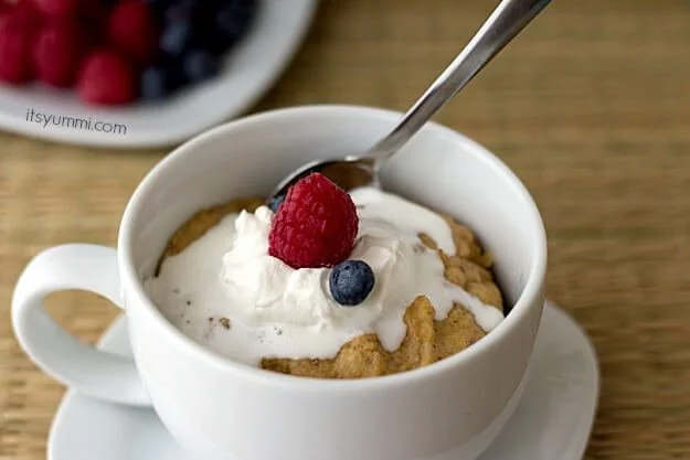 low carb meyer lemon mug cake topped with sugar free whipped cream and fresh berries