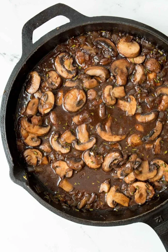 A skillet of glazed mushroom slices for mushroom chicken bourguignon