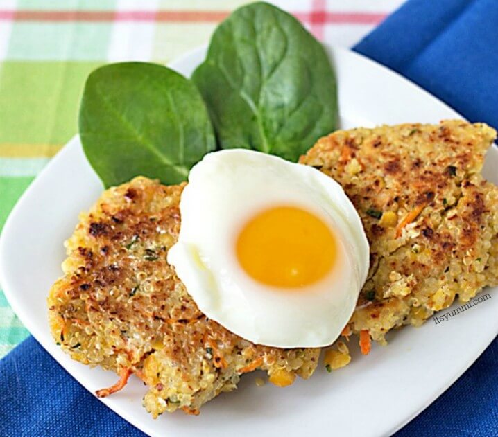 Quinoa Chickpea Patties served on a small white plate with a poached egg and fresh baby spinach leaves