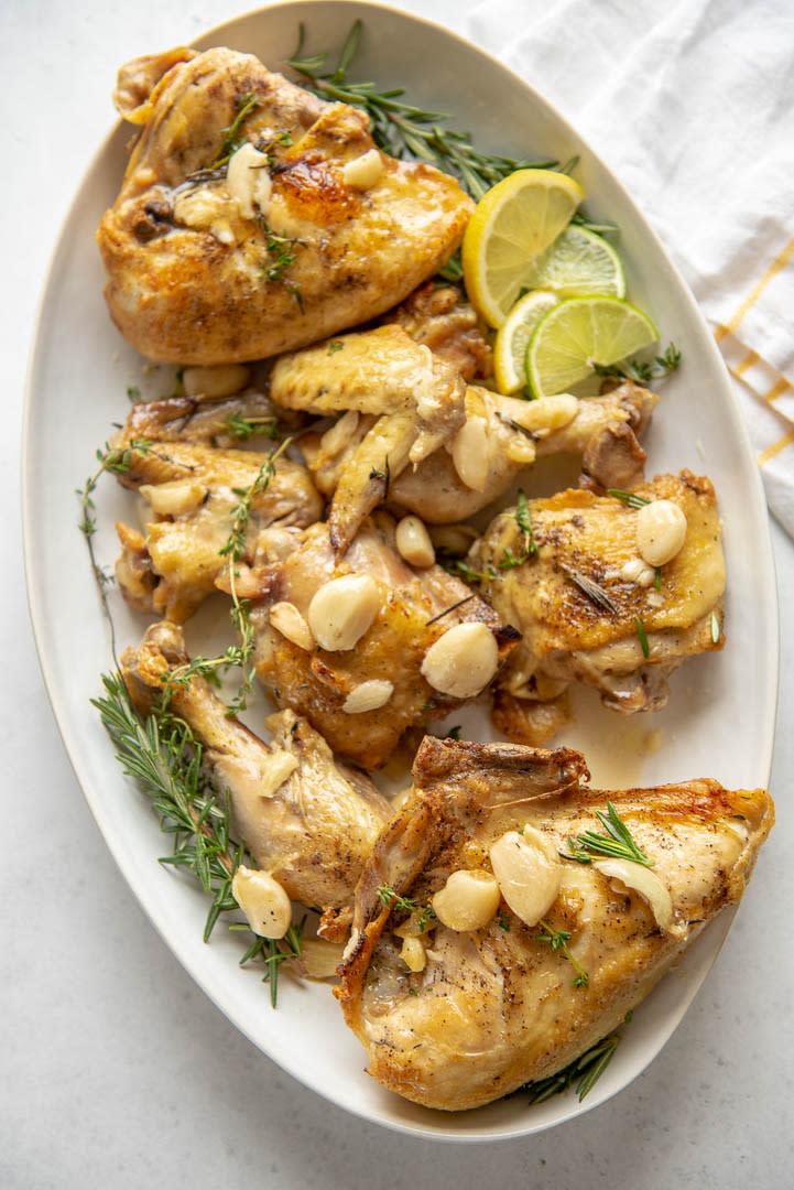 serving platter of oven roasted chicken pieces with garlic cloves and fresh herbs