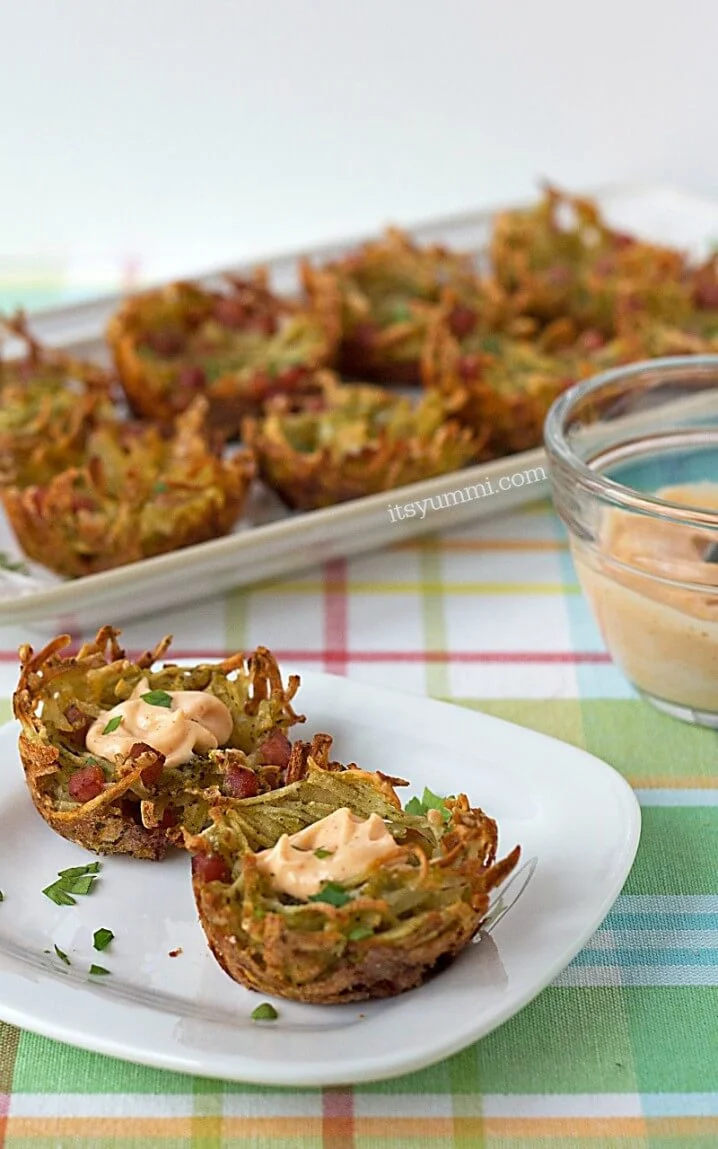 bite sized cheesy hash brown potato nests topped with ham, cheese and spicy aioli #brunch #appetizer #recipe #potatoes small plate and platter holding bite sized cheesy hash brown potato nests topped with ham, cheese and spicy aioli