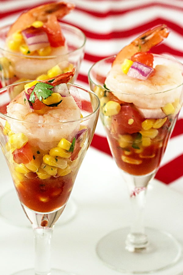 Corn salsa and spicy cocktail sauce make a bed for Jumbo shrimp to rest on in this simple summer appetizer that's easy to make and fun to eat! #cornsalsa #shrimprecipes #appetizers shrimp shooters with fresh corn salsa