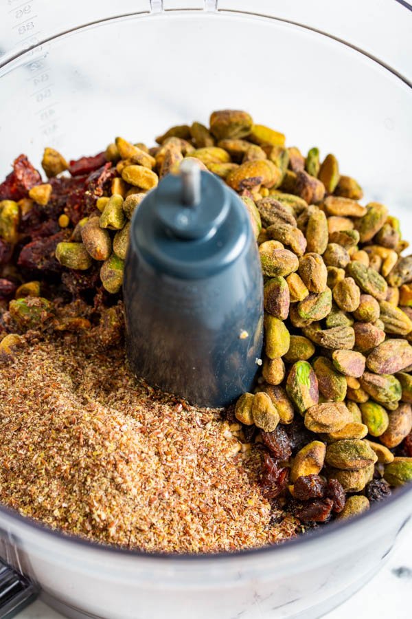 An image of the inside of the food processor with ingredients for no bake pistachio oat cookies