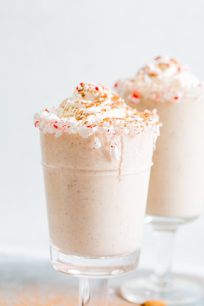 A close up side view of peppermint almond chocolate milkshake with whipped cream and crushed peppermint candies