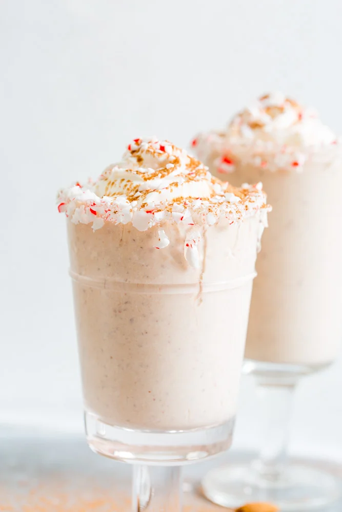 A close up side view of peppermint almond chocolate milkshake with whipped cream and crushed peppermint candies