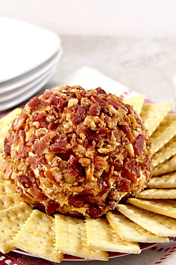 spicy bacon cheese ball on a platter with buttery crackers