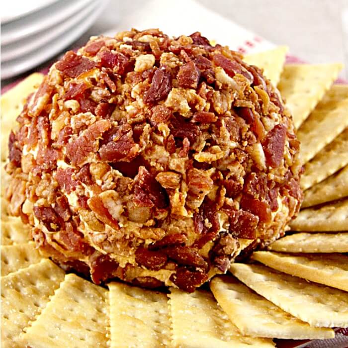 a bacon cheese ball with cream cheese, cheddar cheese, Colby cheese and chipotle peppers on a platter with crackers
