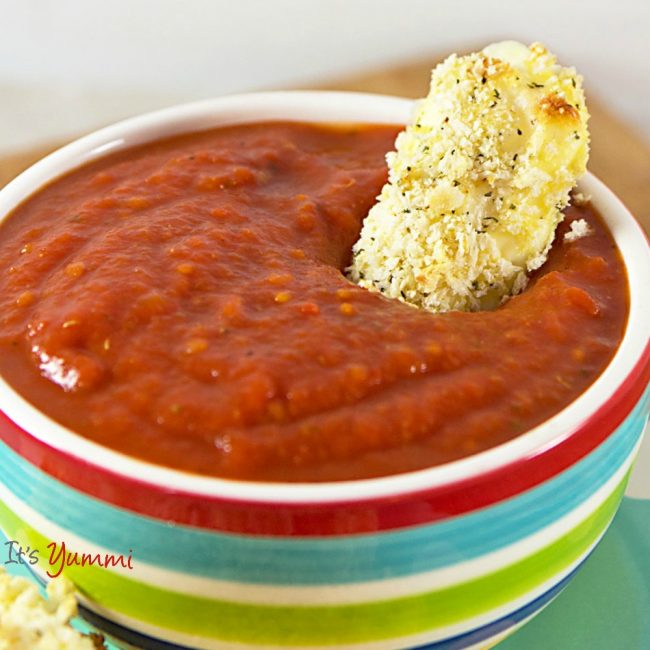 close up image of baked string cheese dipping into marinara sauce