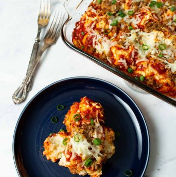 Serving of Biscuit Pizza Bake on Dark Blue Plate with Casserole Dish in upper right corner