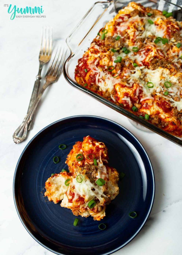 Serving of Biscuit Pizza Bake on Dark Blue Plate with Casserole Dish in upper right corner