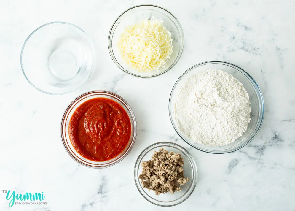 Overhead shot of ingredients spread out needed for Cheese Sausage Biscuit Pizza Bake