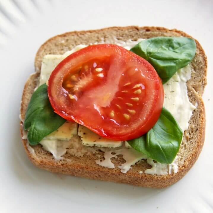 Basil, tomato, and cheese on a slice of Pepperidge Farm<sup>®</sup> Harvest Blends bread.