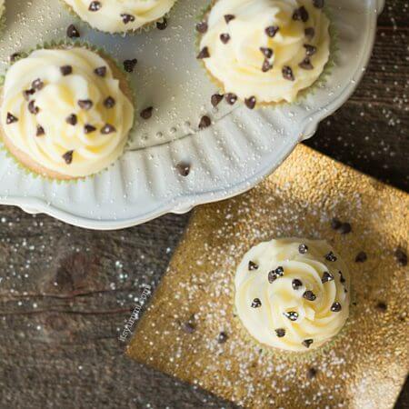 Cannoli cupcakes are inspired by the popular Italian dessert. Moist cinnamon cupcakes, topped with fluffy mascarpone buttercream and a sprinkling of chocolate chips and powdered sugar. Recipe on itsyummi.com
