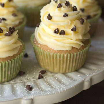 Cannoli cupcakes are inspired by the popular Italian dessert. Moist vanilla cupcakes, topped with fluffy mascarpone buttercream and a sprinkling of chocolate chips and powdered sugar. Recipe on itsyummi.com