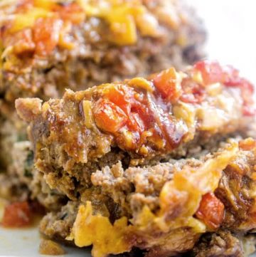 Veggie stuffed meatloaf is the best meatloaf I've ever eaten - complete comfort food. Ground pork and beef meatloaf is stuffed with spinach, onions, and cheese, then topped with barbecue sauce, tomatoes, and more cheese! #meatloaf #recipe #dinner