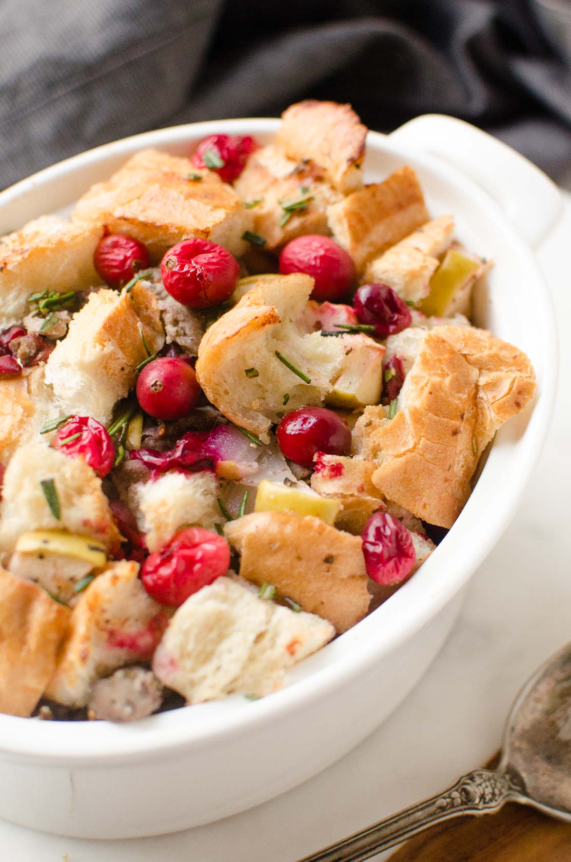 3/4 angle on cranberry sausage stuffing in oval white casserole dish