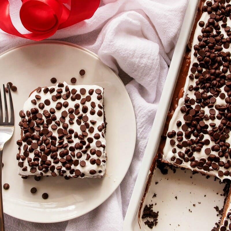 pan and plate of chocolate dessert lasagna - chocolate lasagna is a layered no bake dessert made with chocolate cookies, chocolate pudding, whipped cream, and chocolate chips