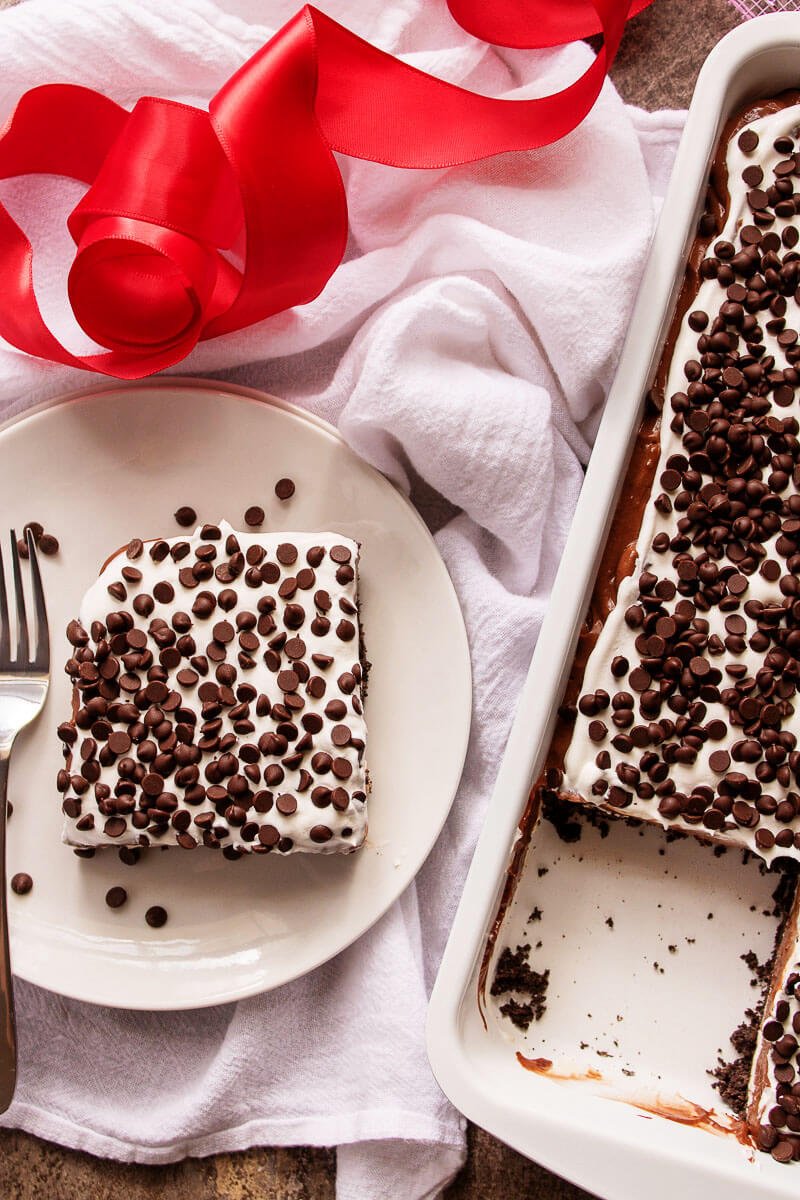 pan of chocolate dessert lasagna with a slice removed - chocolate lasagna is a layered no bake dessert made with chocolate cookies, chocolate pudding, whipped cream, and chocolate chips. #dessert #nobake #recipe #lush