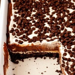 pan of chocolate dessert lasagna with a slice removed - chocolate lasagna is a layered no bake dessert made with chocolate cookies, chocolate pudding, whipped cream, and chocolate chips