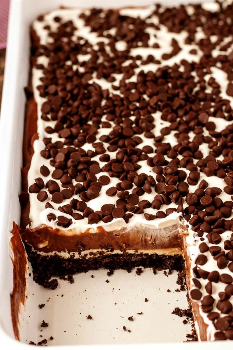 pan of chocolate dessert lasagna with a slice removed - chocolate lasagna is a layered no bake dessert made with chocolate cookies, chocolate pudding, whipped cream, and chocolate chips. #dessert #nobake #recipe #lush