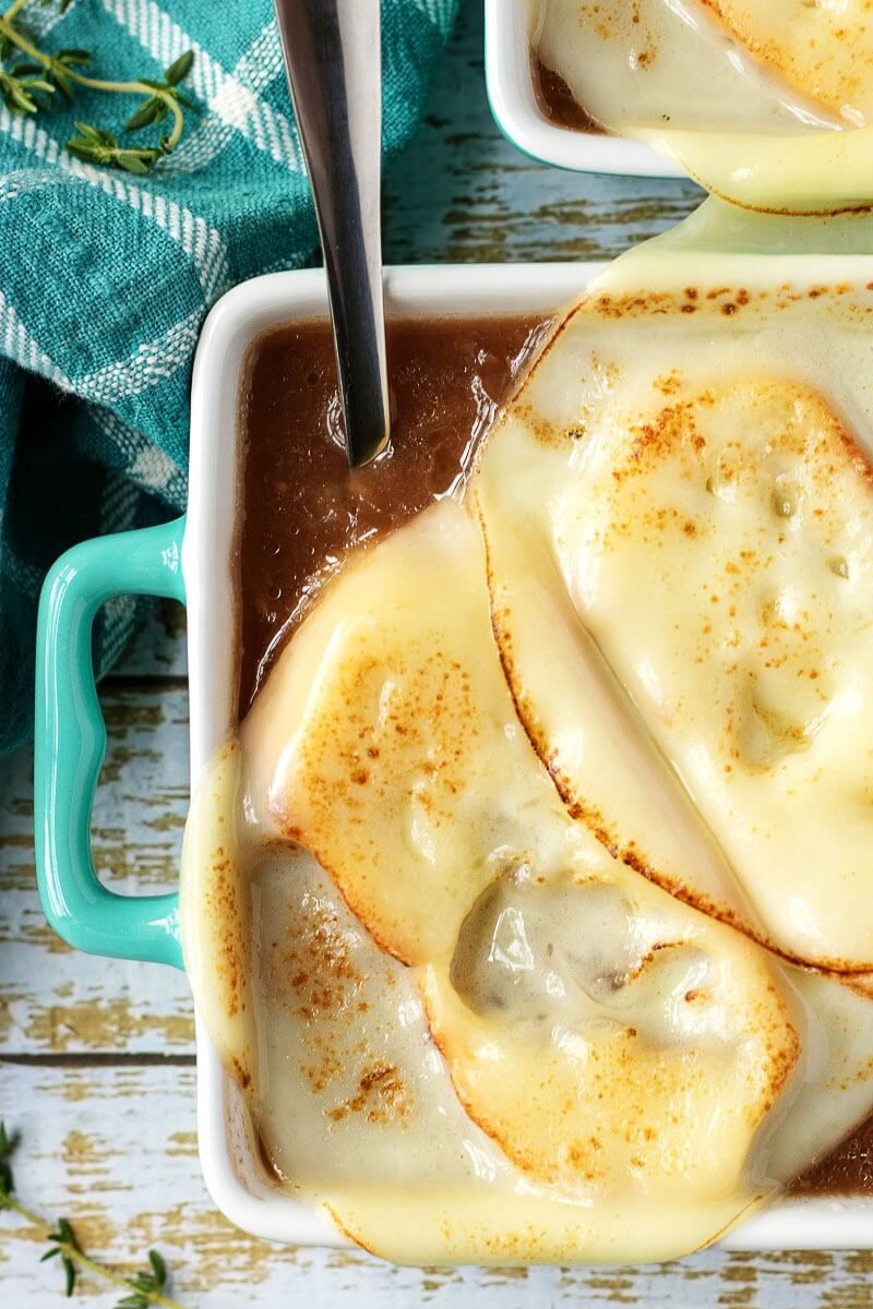 soup crock filled with French onion soup, topped with a crispy crouton and melted cheese over the top of it