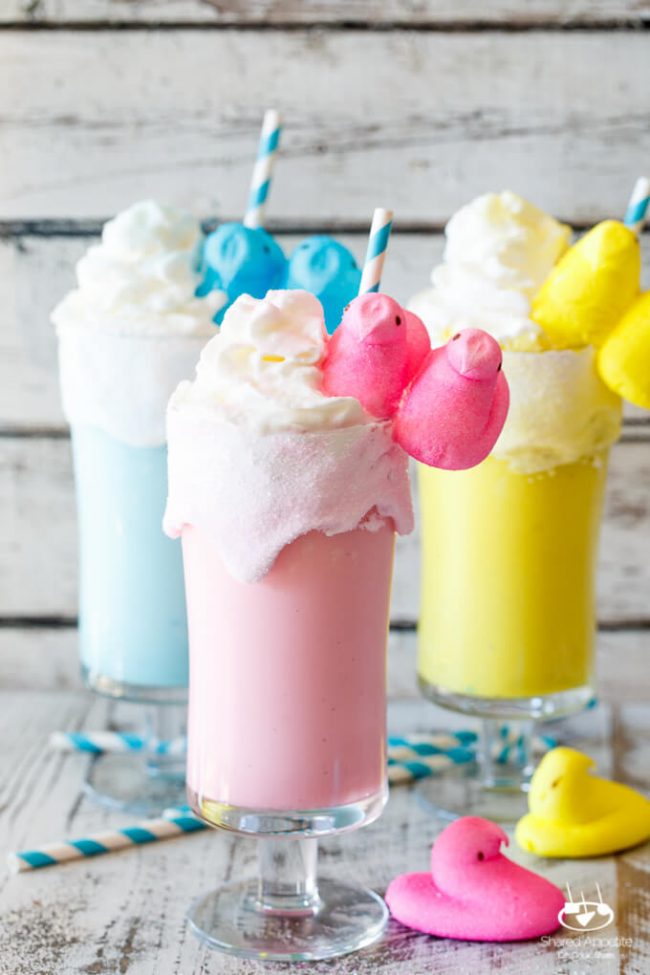 3 glasses of pastel colored milkshakes made using Easter marshmallow Peeps. Glasses are rimmed with 2 marshmallow Peeps