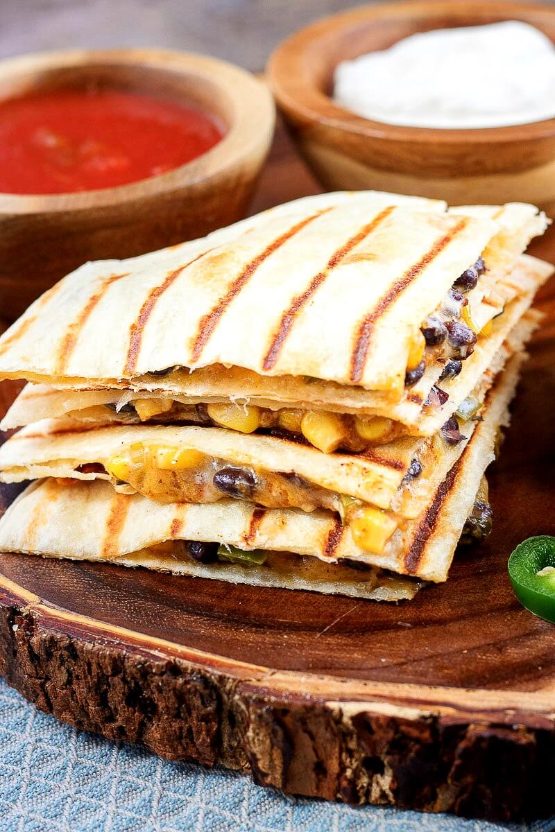 vegetarian quesadillas filled with spicy corn and black bean mixture and cheese on a natural wood serving platter (with bark exterior)