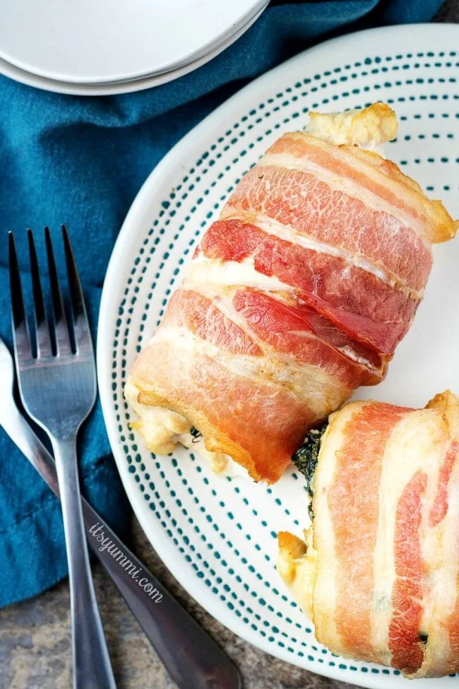 Bacon wrapped chicken roll ups - boneless chicken breasts stuffed with cream cheese and spinach, wrapped with bacon. These baked chicken bundles are low carb and SO good. #quickdinner #chicken #recipe #easydinner #lowcarb overhead image of low carb chicken breast bundles stuffed with spinach and cheese, wrapped in bacon