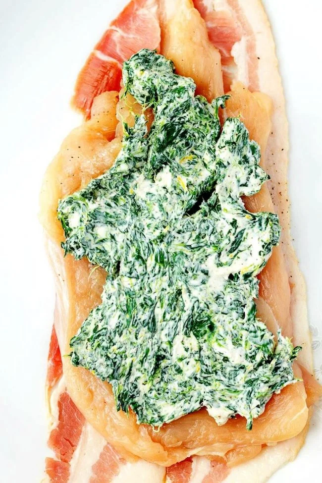 Bacon wrapped chicken roll ups - boneless chicken breasts stuffed with cream cheese and spinach, wrapped with bacon. These baked chicken bundles are low carb and SO good. #quickdinner #chicken #recipe #easydinner #lowcarb cream cheese and spinach filling spread onto a flattened chicken breast for a chicken rollups recipe