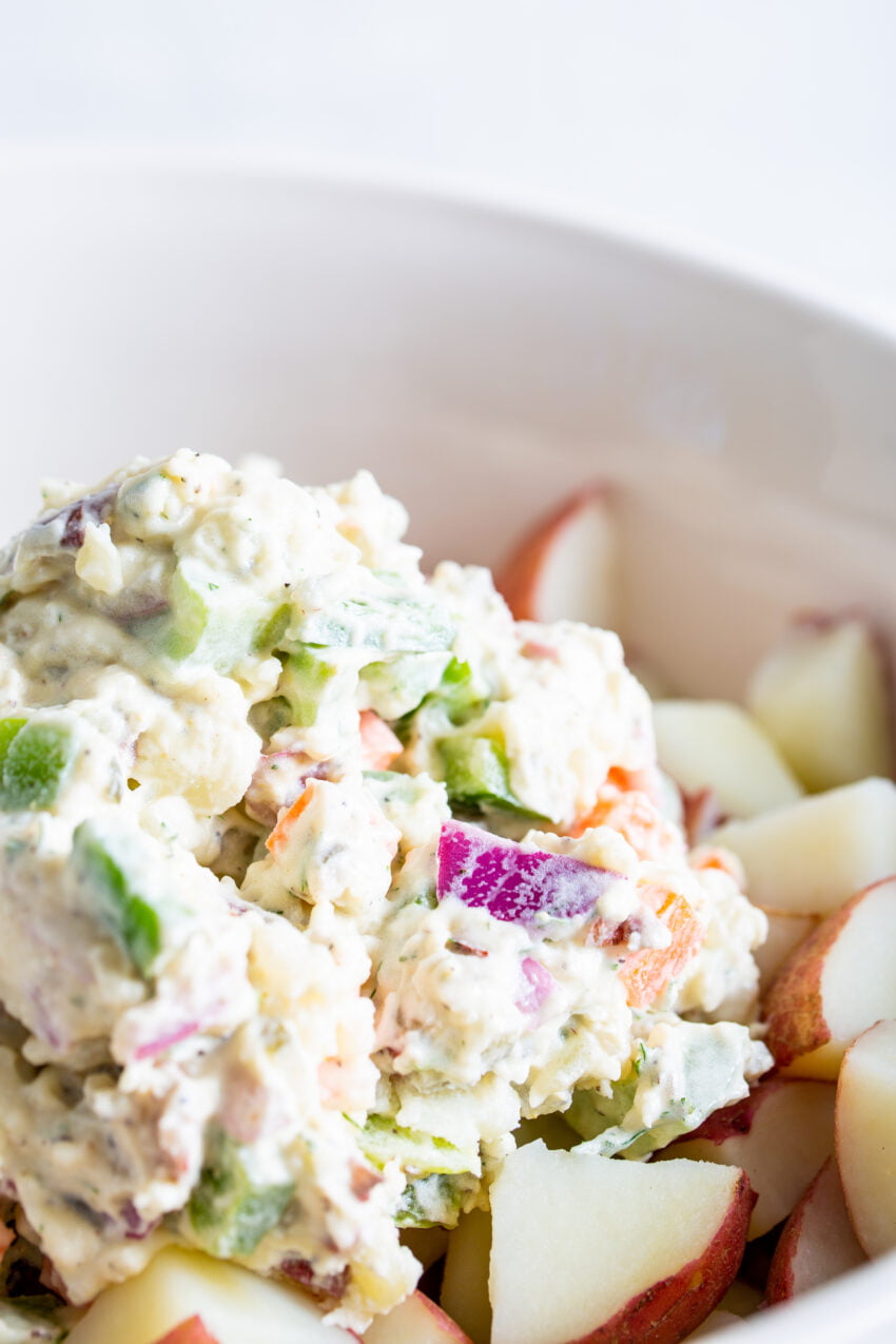 A close up process shot making potato salad with farm fresh veggies