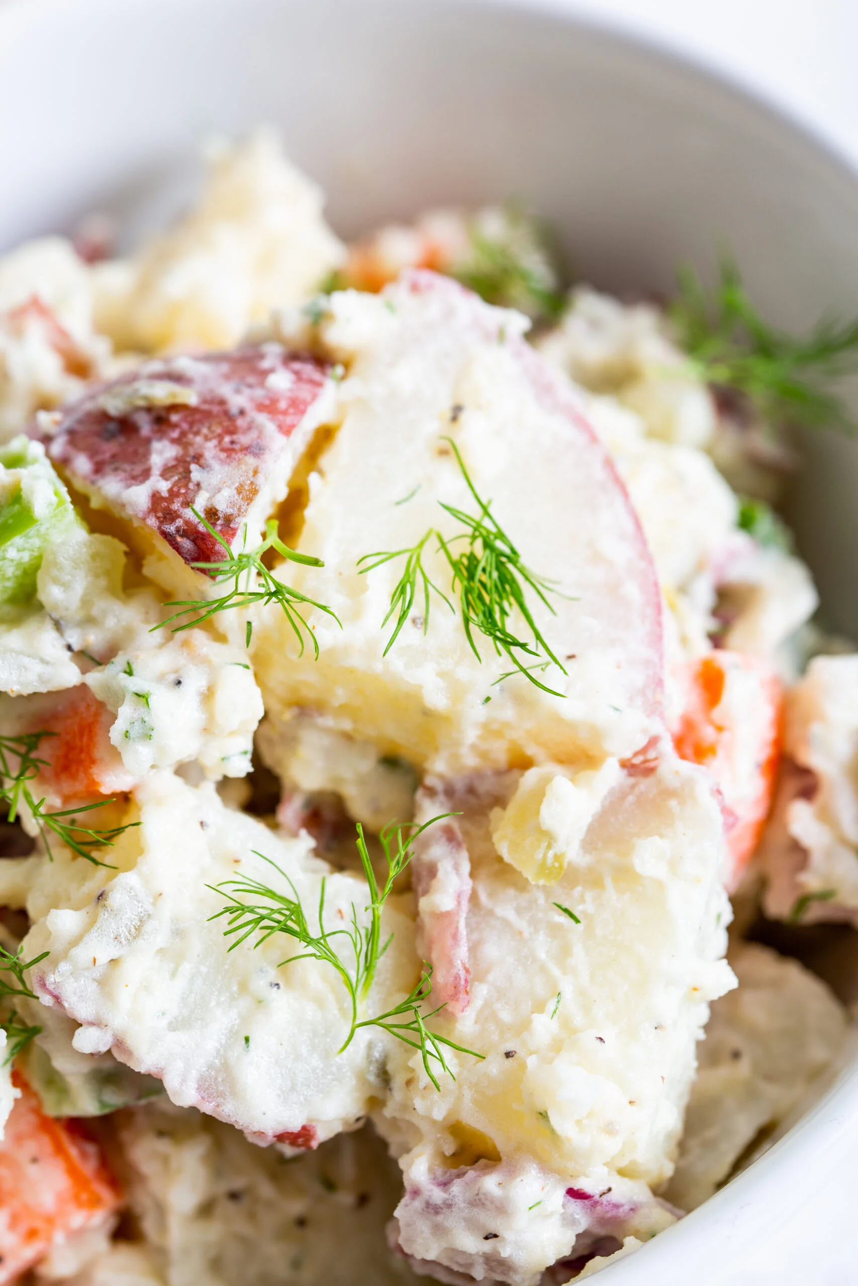 a close up view of farmers market potato salad in a white bowl