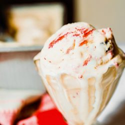 dessert dish of strawberry cookie dough ice cream with ice cream melting down the side of the dish