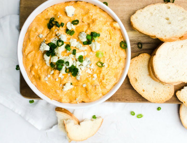 bowl of spicy chicken dip topped with blue cheese crumbles