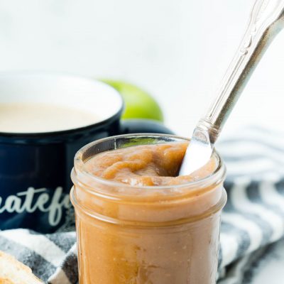 Up close of apple butter in jar with knife.