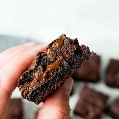 Image of: a hand holding the best brownie ever with melted chocolate coming out the middle.