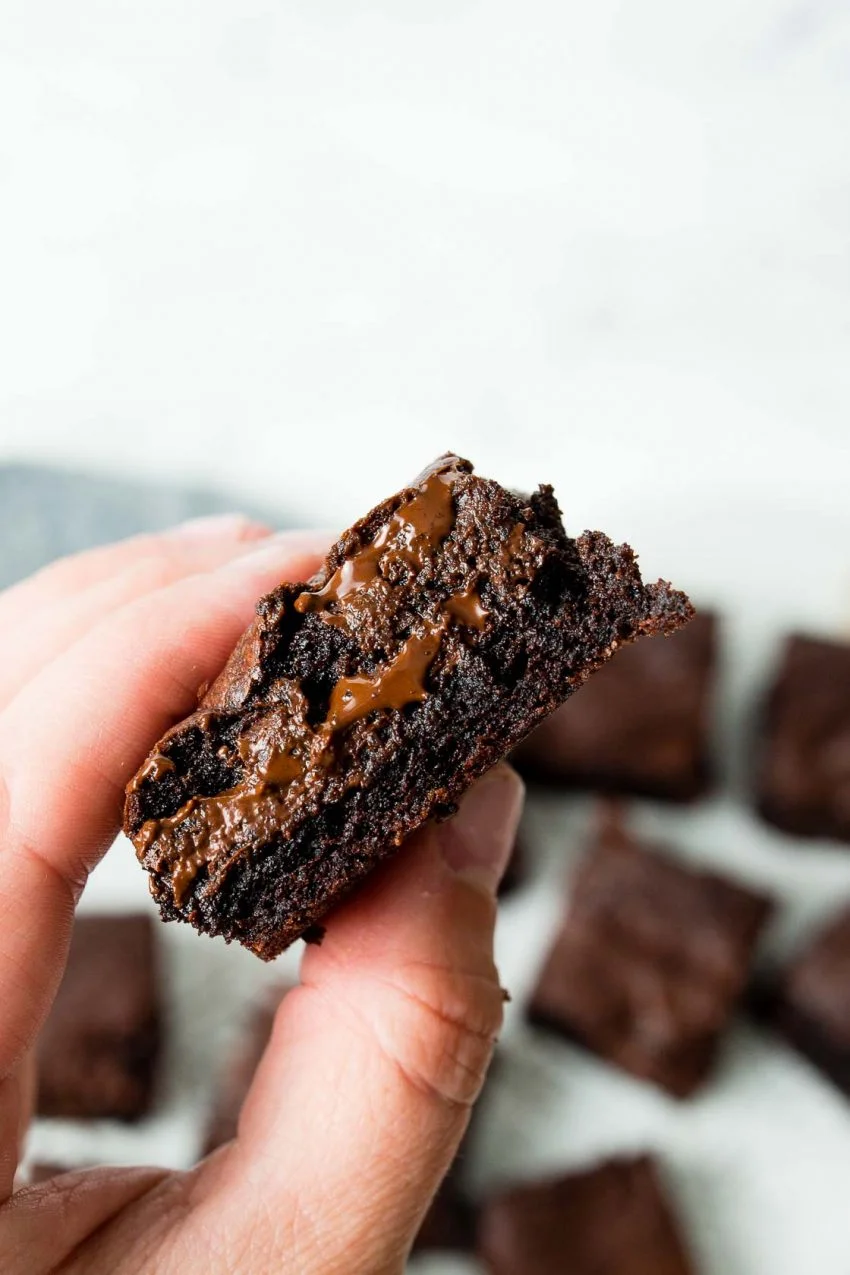 Image of: a hand holding the best brownie ever with melted chocolate coming out the middle.