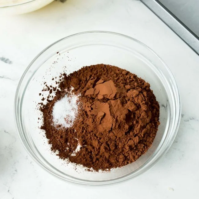 A glass bowl of flour, cocoa powder, and salt.