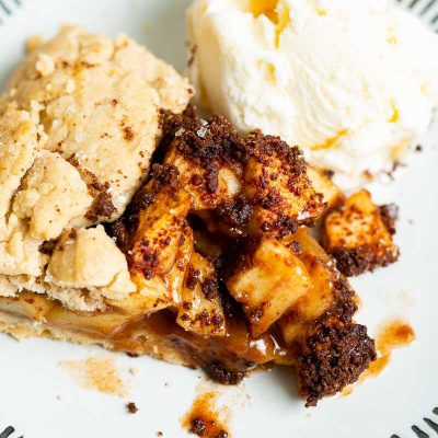 A closeup of apple galette on a white plate served with vanilla ice cream.