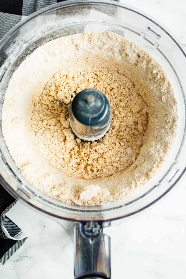 Liquid ingredients are added to the dry ingredients in the food processor to combine.