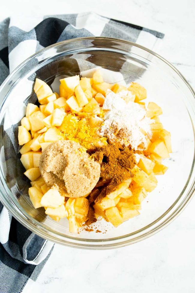 Ingredients for an apple galette filling are combined in one large bowl.