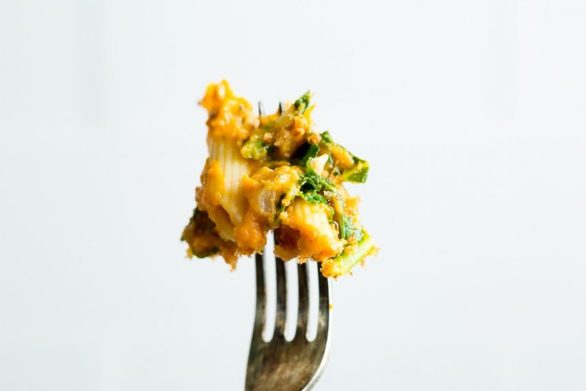 A close up image of creamy turkey pumpkin pasta on a fork 