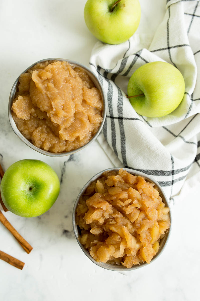 two bowls of chunky slow cooker applesauce with apples around