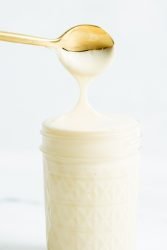 A closeup image of a gold spoon dipped in sweetened condensed milk.