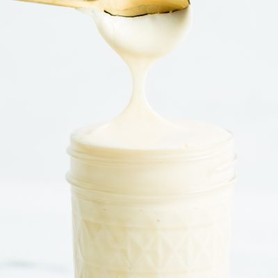 A closeup image of a gold spoon dipped in sweetened condensed milk.