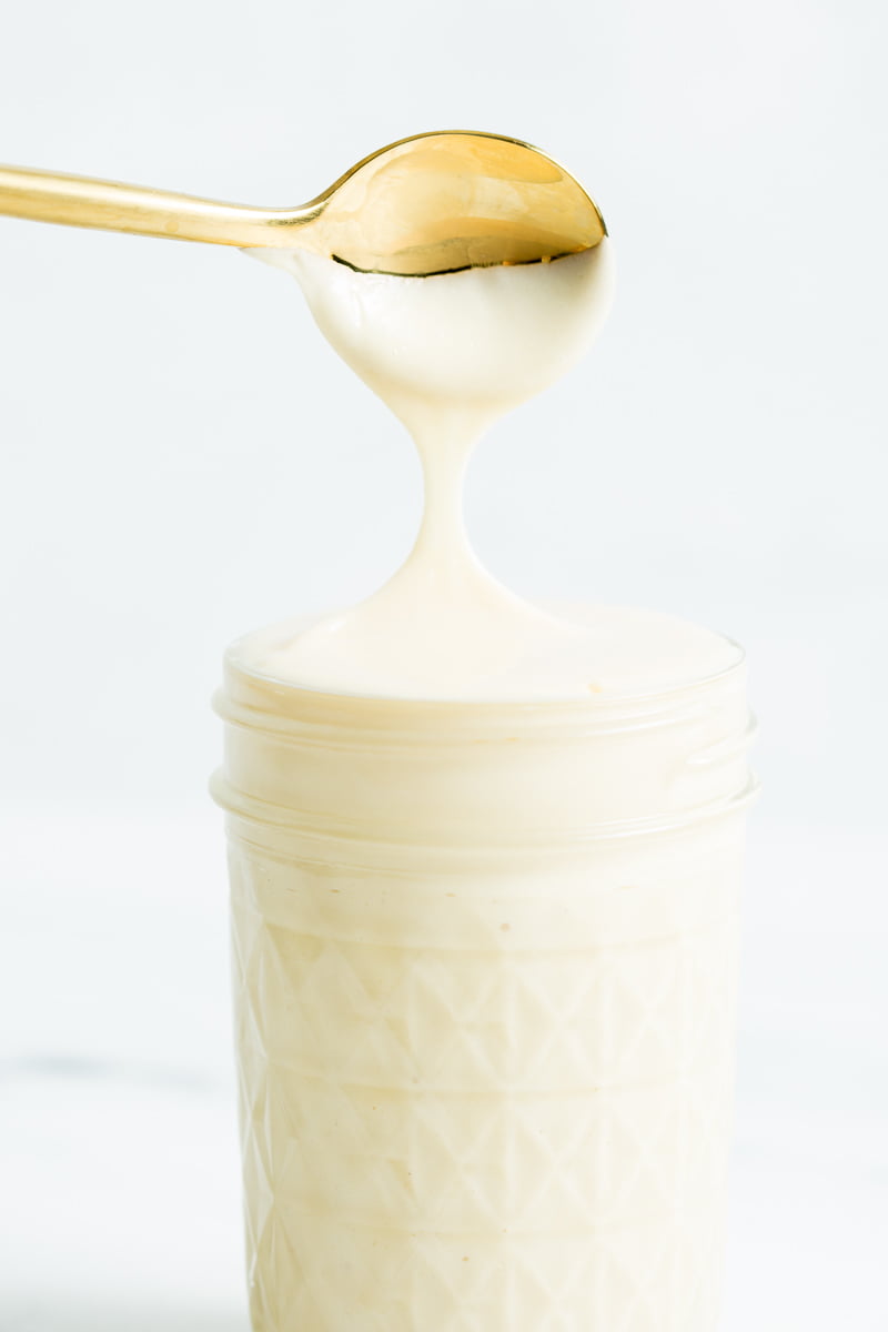 A closeup image of a gold spoon dipped in sweetened condensed milk.